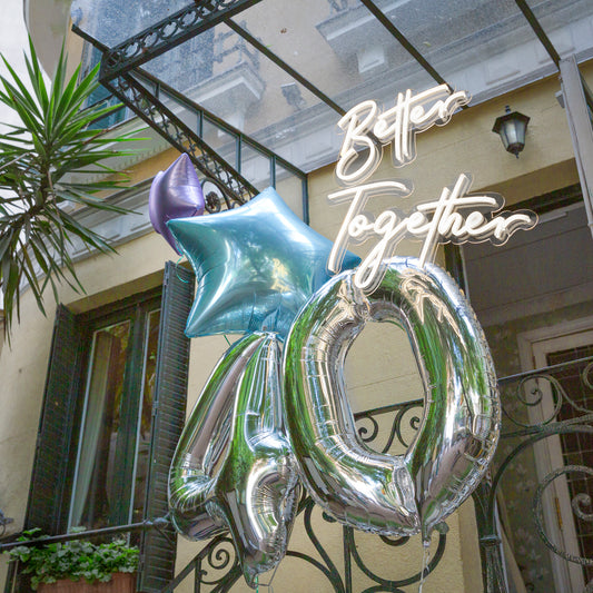 Composición de globos diseñada por By Ana Laborda en el restaurante de La Favorita en Madrid, en tonos fríos y neón Better Together delante de la fachada