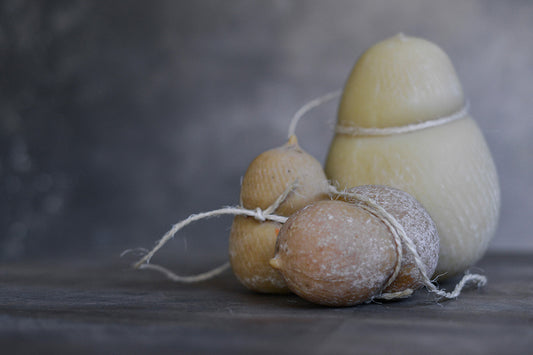 Estilismo fotográfico realizado por By Ana Laborda para Quesería Zucca, en la foto tres quesos curados con su cuerda rústica, sobre mesa de madera